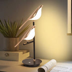 Elegant Bellvian bird LED lamp on dark bedside table, luxury bedroom lighting setup with warm golden glow.