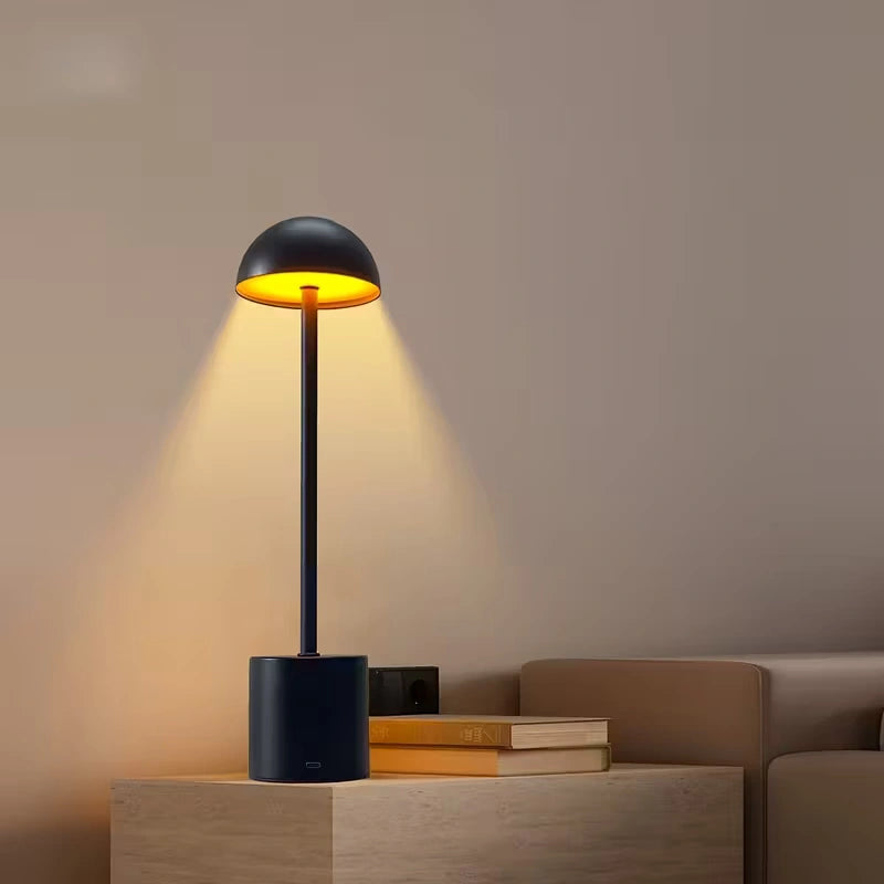 Elegant black LED table lamp emitting golden ambient light, perfect for living rooms, restaurants, and study areas. Bellvian modern cordless lamp for UK interiors.