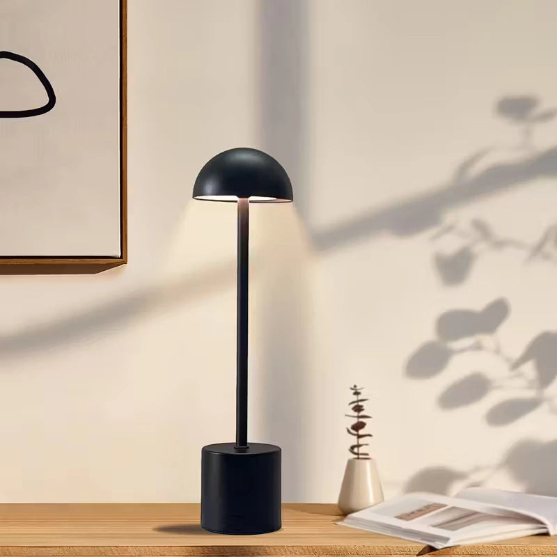 Minimalist black LED table lamp with natural daylight shadows on wooden desk, ideal for home offices or Scandinavian-style interiors. Bellvian UK lighting collection.