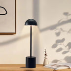 Minimalist black LED table lamp with natural daylight shadows on wooden desk, ideal for home offices or Scandinavian-style interiors. Bellvian UK lighting collection.