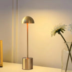 Champagne gold LED table lamp beside a vase with flowers, creating a warm and elegant atmosphere. Ideal for living rooms, bedrooms, and hotel interiors. Bellvian collection.