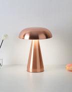 Copper mushroom LED desk lamp on a clean white surface, casting warm ambient light; portable, rechargeable and perfect as a bedside lamp.