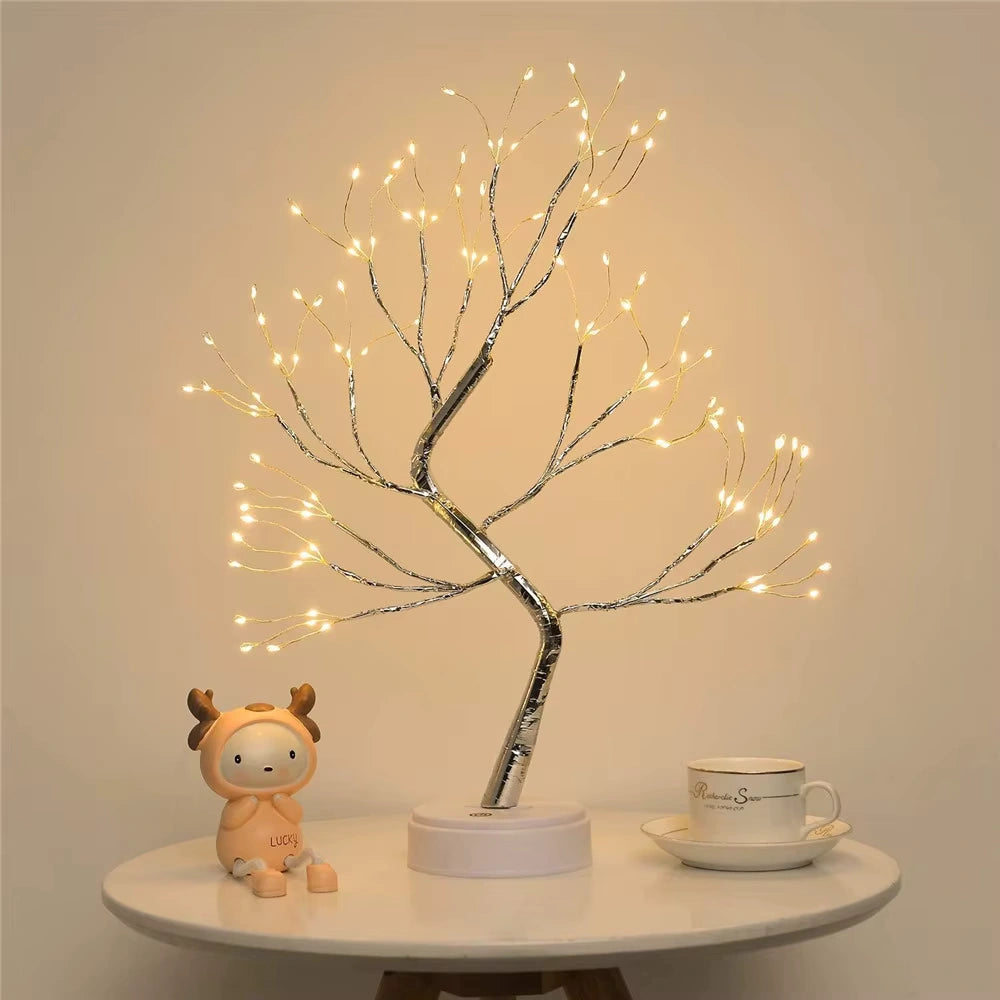 Fairy Light Spirit Tree Lamp with delicate silver branches on a round table beside a ceramic mug and cute reindeer toy  charming night lamp for cozy home interiors.