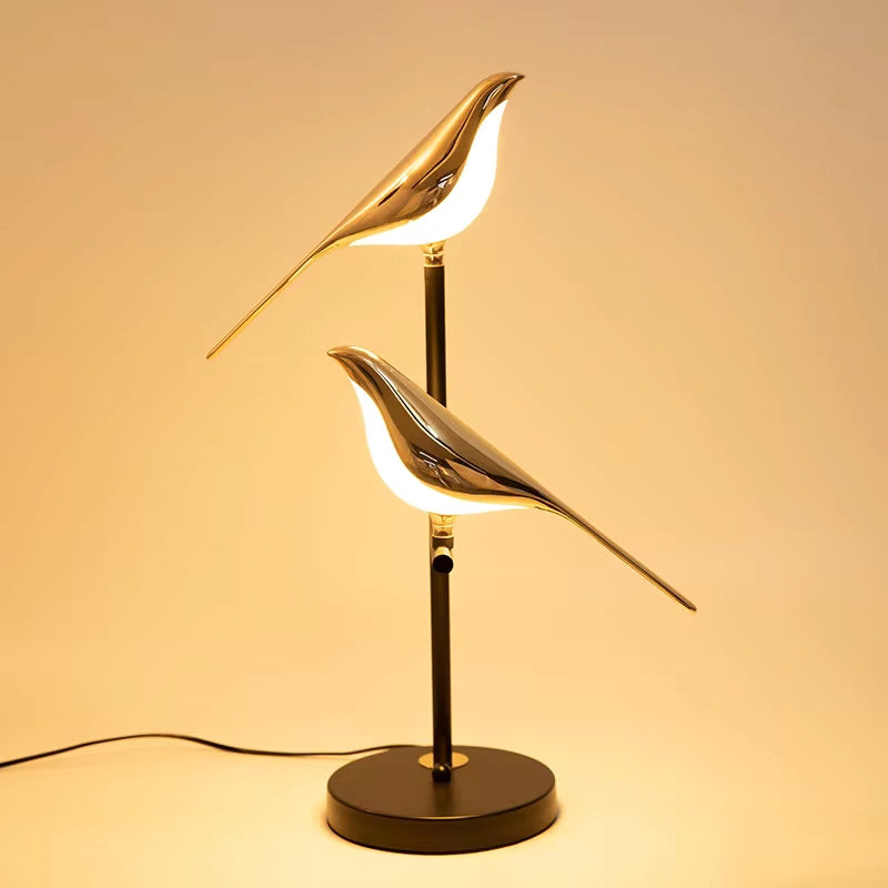 Dual-head golden Bellvian LED bird lamp glowing warmly, perfect modern bedside lighting for reading and decor.