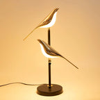 Dual-head golden Bellvian LED bird lamp glowing warmly, perfect modern bedside lighting for reading and decor.