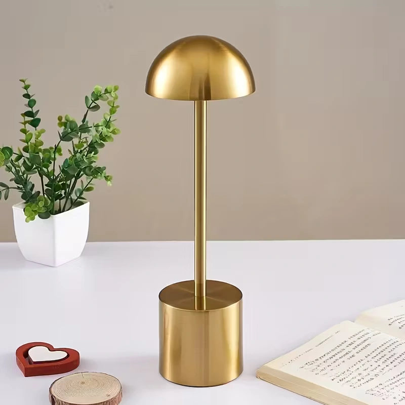 Luxurious gold metal LED table lamp with glossy finish, placed on a white desk beside books and plants. Modern home lighting by Bellvian 