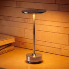 Bellvian silver aluminum LED table lamp standing on a dining table in a modern restaurant interior, emitting soft neutral white light for elegant evening ambience.