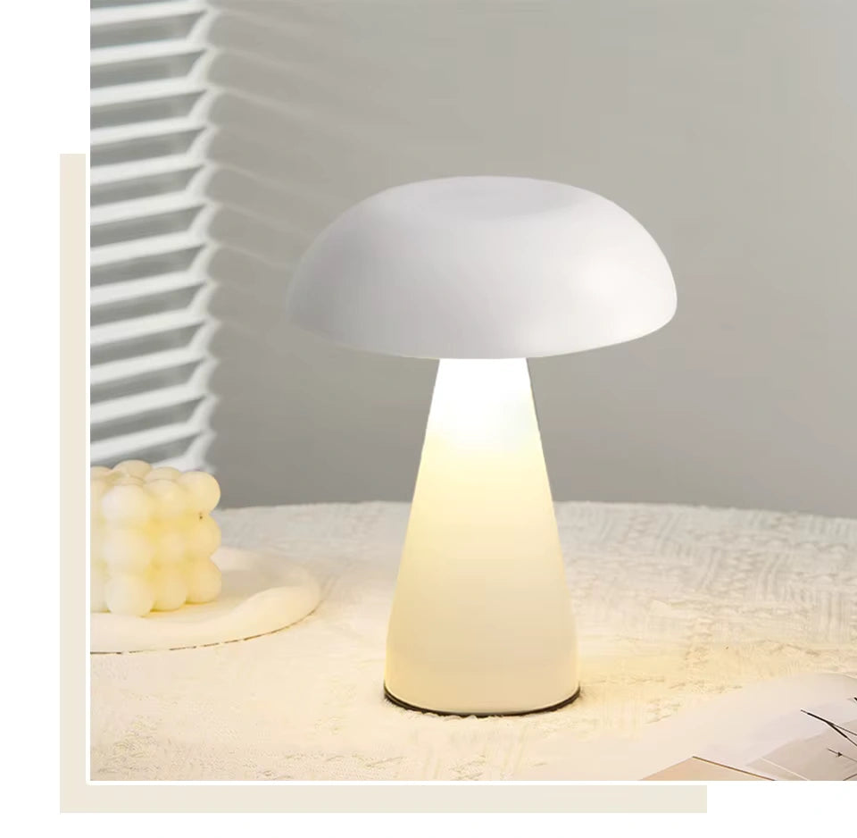 White mushroom night light with soft warm LED glow on a table; portable, cordless and dimmable for cosy bedroom ambience.
