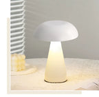 White mushroom night light with soft warm LED glow on a table; portable, cordless and dimmable for cosy bedroom ambience.