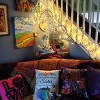 Bohemian-style living room with Bellvian Willow Vine String Lights wrapped along the staircase, creating a cozy and artistic home ambiance.
