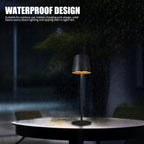 Black waterproof LED table lamp designed for outdoor use, shown glowing beautifully under light rain. Durable, rechargeable, and perfect for patios, gardens, and restaurants.