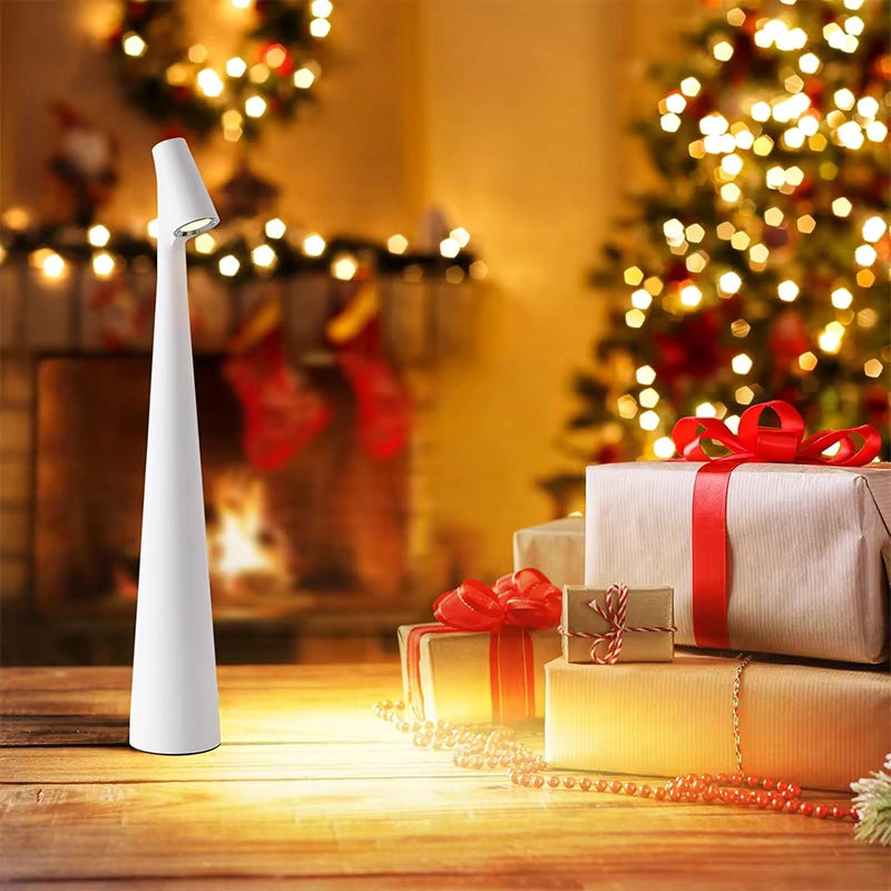 White LED table lamp glowing warmly beside Christmas presents and festive decorations in front of a glowing Christmas tree and fireplace perfect holiday ambiance lighting. Bellvian