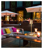 Gold LED table lamp lighting up a stylish restaurant patio with candles and seating. Adds a luxurious touch to modern hospitality settings, cafés, and hotel terraces.
