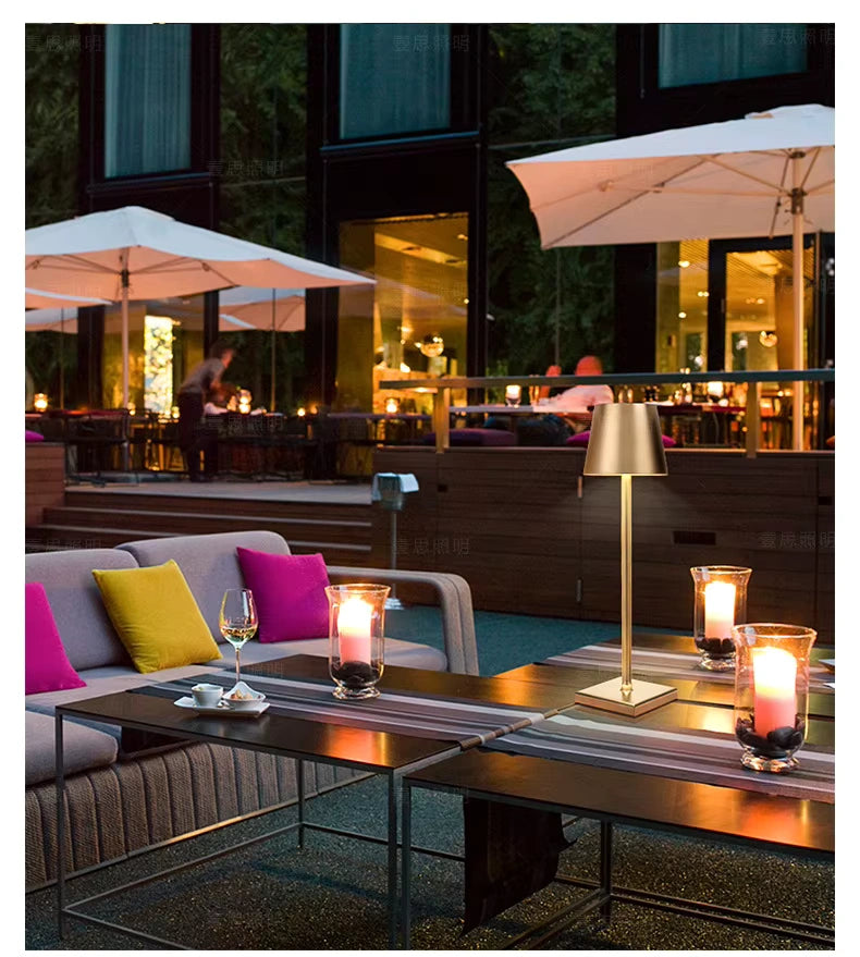 Gold LED table lamp lighting up a stylish restaurant patio with candles and seating. Adds a luxurious touch to modern hospitality settings, cafés, and hotel terraces.