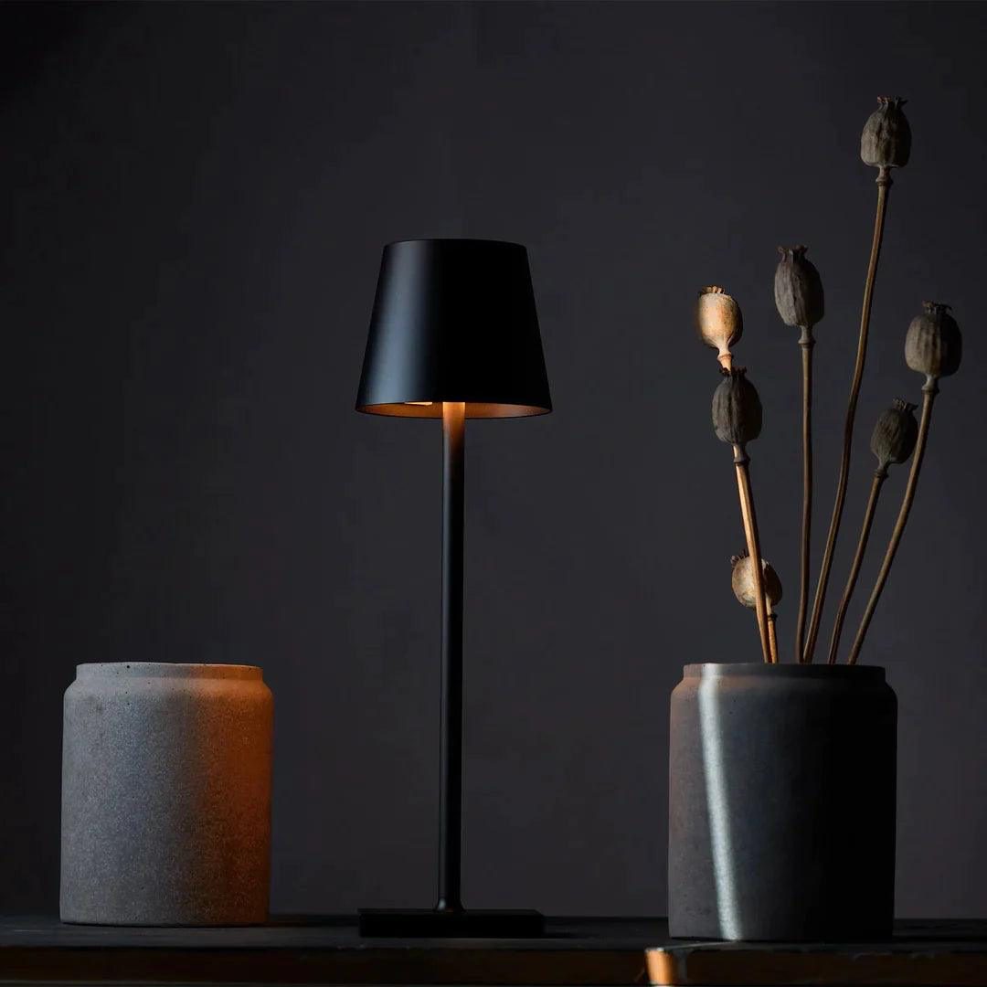 Black LED table lamp emitting a soft warm light in a dark modern interior. Ideal for night ambiance, reading, or decorative lighting in contemporary spaces.