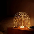 LED willow tree bedside lamp with soft golden lights illuminating a wooden nightstand in a dimly lit bedroom. The warm light creates a relaxing and intimate atmosphere for nighttime use and cozy home decor.