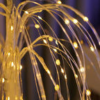 Close-up view of LED willow tree lamp showing flexible transparent branches with glowing warm yellow fairy lights. The intricate wire details highlight the lamp’s elegant craftsmanship and ambient lighting design for modern interiors.