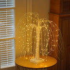 LED willow tree lamp positioned near a window, glowing softly in a warm-toned room. The cascading lights and white trunk add an elegant, nature-inspired touch to modern home interiors and evening lighting decor. Bellvian