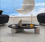 Two modern cordless LED table lamps, one white and one gold, displayed on a sleek black coffee table in a minimalist living room with ocean view and stylish contemporary furniture.