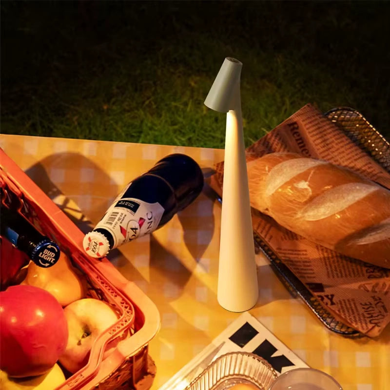 Cordless white LED lamp illuminating a picnic table with fruits, bread, and drinks under warm ambient evening light, showcasing outdoor versatility and cozy design. Bellvian